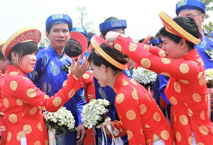 Các cô dâu chỉnh trang trang phục cho nhau để làm lễ dâng hoa tại tượng đài Chủ tịch Hồ Chí Minh trước giờ vào nghi lễ cưới - Ảnh: Q.LINH 