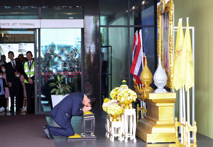 Ông Thaksin cúi lạy chân dung nhà vua sau khi về nước - Ảnh: REUTERS