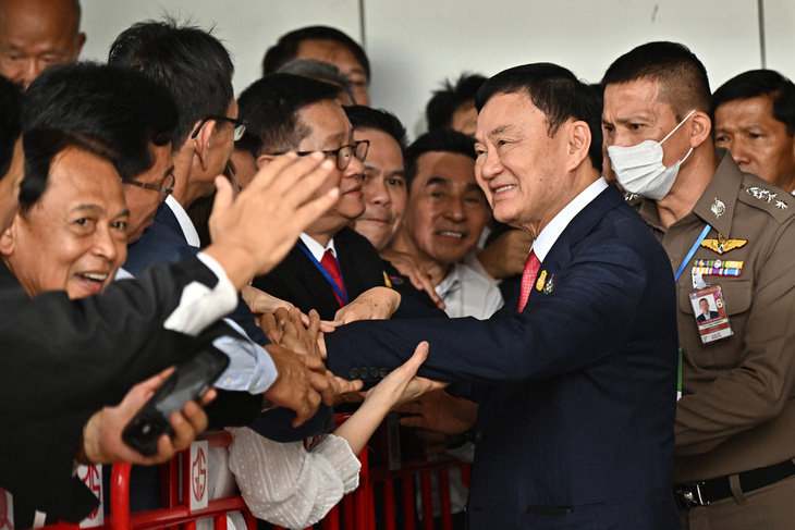 Ông Thaksin bắt tay người ủng hộ trước khi được đưa đến tòa án - Ảnh: AFP