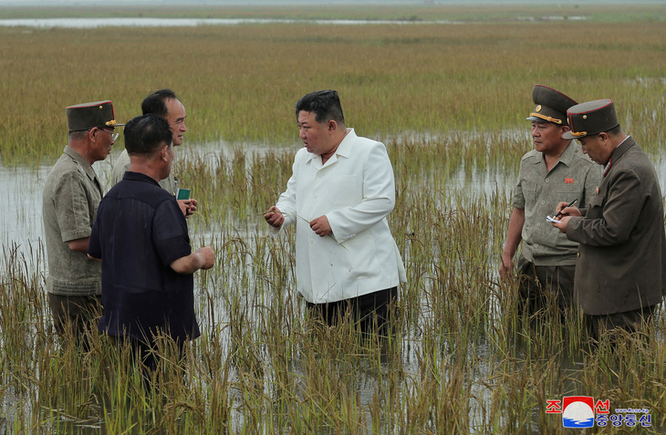 Ông Kim trao đổi cùng một số quan chức Triều Tiên ngay dưới ruộng - Ảnh: REUTERS