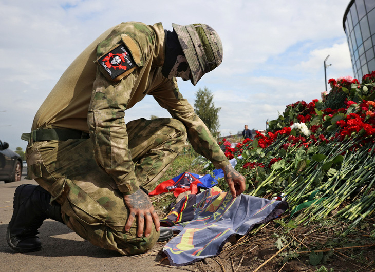 Một lính đánh thuê Wagner đặt hoa tưởng niệm ông trùm Yevgeny Prigozhin ở Saint Petersburg, Nga, ngày 24-8 - Ảnh: REUTERS
