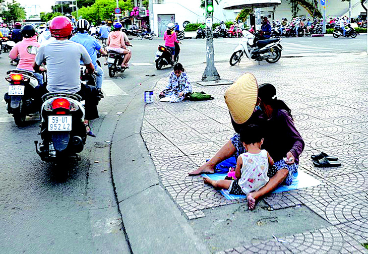 Nhiều người lợi dụng trẻ em đi xin tiền ở giao lộ tại TP.HCM - Ảnh: T.T.D.