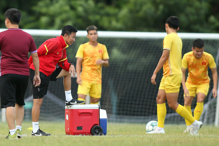HLV Hoàng Anh Tuấn (áo đỏ) có phút giây suy tư trong buổi tập trước trận U23 Việt Nam đấu với U23 Indonesia - Ảnh: HOÀNG TÙNG