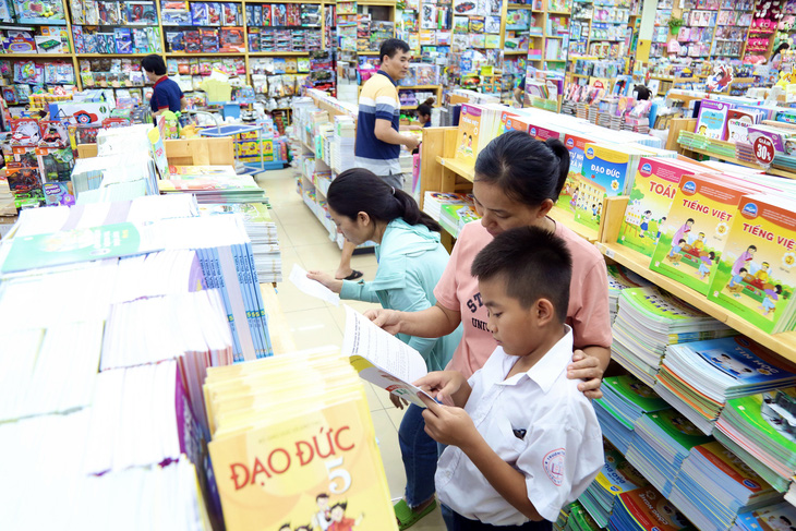Em Trương Lương Bình (học sinh lớp 5 Trường tiểu học Cổ Loa, quận Phú Nhuận) cùng phụ huynh chọn mua sách tại nhà sách Phú Nhuận chiều 25-8 - Ảnh: PHƯƠNG QUYÊN