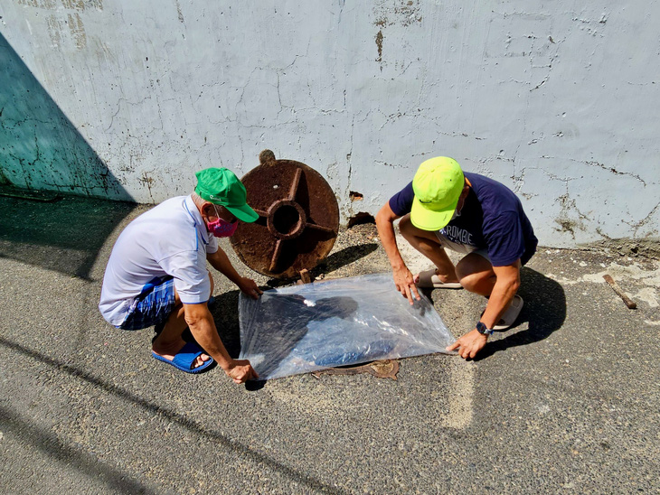 Người dân đường Đặng Dung (phường Phước Long, thành phố Nha Trang) phải dùng tấm nhựa bịt miệng cống cho khỏi bốc mùi - Ảnh: MINH CHIẾN