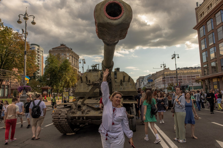 Một người phụ nữ Ukraine tạo dáng chụp hình trước xe tăng bị phá hủy của Nga đang được trưng bày công khai ở Kiev, ngày 24-8 - Ảnh: AFP