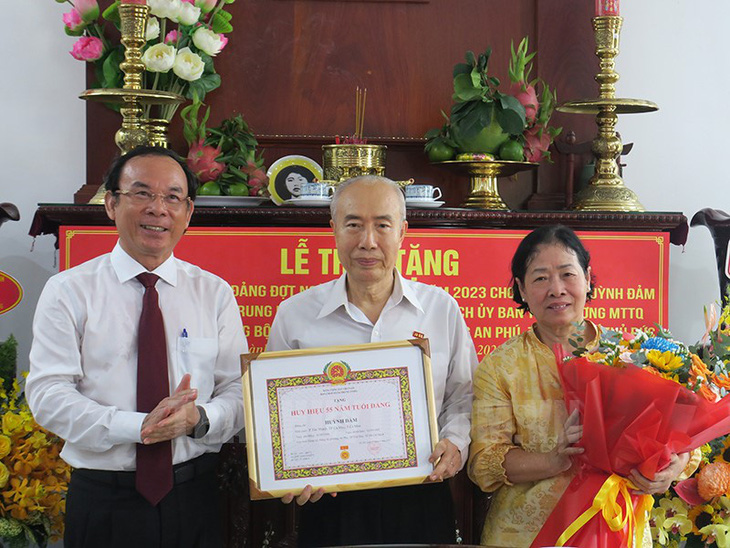 Bí thư Thành ủy TP.HCM Nguyễn Văn Nên (bìa trái) trao tặng huy hiệu 55 năm tuổi Đảng và hoa chúc mừng ông Huỳnh Đảm - Ảnh: THÀNH ỦY TP.HCM
