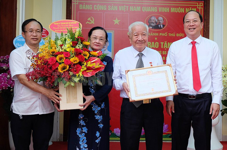 Phó bí thư Thành ủy TP.HCM Nguyễn Hồ Hải (bìa phải) trao huy hiệu đảng và tặng hoa chúc mừng trung tướng Võ Thái Hòa - Ảnh: THÀNH ỦY TP.HCM