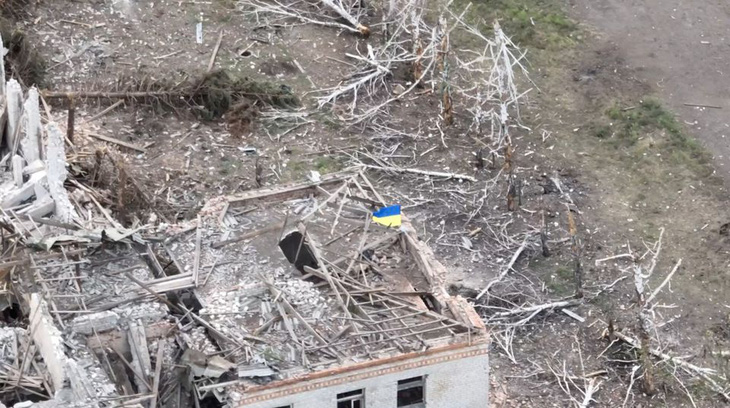 Ảnh cắt từ đoạn video đăng trên mạng xã hội hôm 23-8, trong đó cho thấy lá cờ Ukraine được cắm trên một tòa nhà tại làng Robotyne - Ảnh: REUTERS