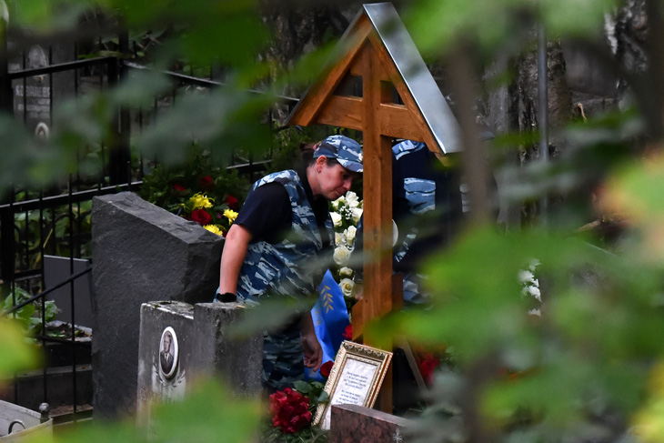 Một sĩ quan cảnh sát đứng cạnh ngôi mộ được cho là của ông Prigozhin - Ảnh: AFP