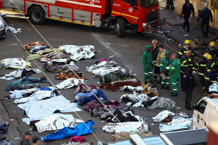 Thi thể các nạn nhân thiệt mạng trong vụ cháy sáng sớm 31-8 ở thủ đô Johannesburg được đặt gần hiện trường, đợi thân nhân đến xác nhận - Ảnh: REUTERS