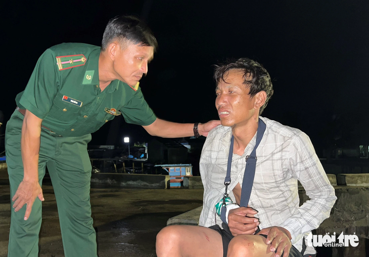 Cán bộ biên phòng hỏi thăm sức khỏe của ngư dân Huỳnh Văn Hoanh (43 tuổi, chủ tàu kiêm máy trưởng) bị gãy tay phải - Ảnh: T.M.