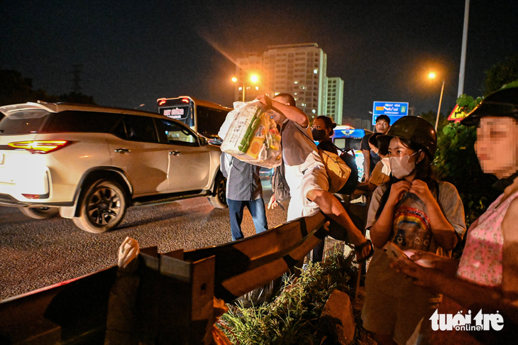 Trên tuyến cao tốc Pháp Vân - Cầu Giẽ lúc nửa đêm, nhiều người trèo rào vào trong cao tốc để đón xe khách - Ảnh: HỒNG QUANG