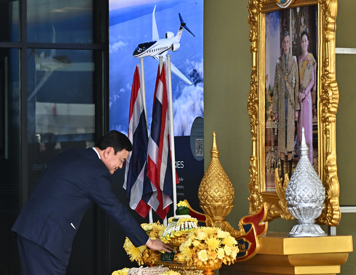 Ông Thaksin cúi lạy chân dung Quốc vương Thái Lan ngay sau khi về nước hôm 22-8 - Ảnh: REUTERS