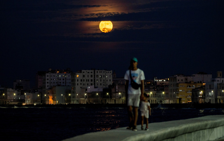 Hai cha con đi dạo dưới bầu trời có siêu trăng xanh tại thủ đô Havana (Cuba) - Ảnh: AFP