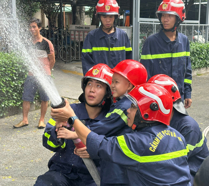 Bé Trung Quân cười khoái chí khi cùng các chiến sĩ Phòng Cảnh sát phòng cháy chữa cháy và cứu nạn cứu hộ (PC07) Công an TP.HCM cầm lăng phun "chữa cháy" - Ảnh: BVCC