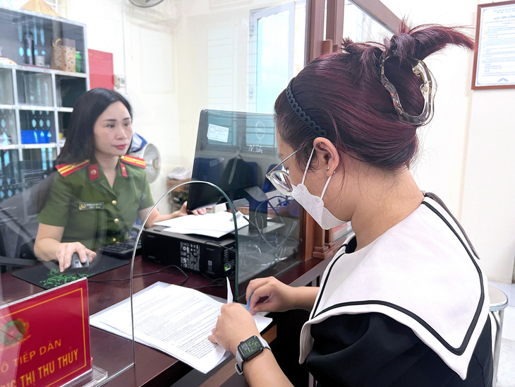 Người dân hỏi thủ tục đăng ký thông tin tạm trú tại công an một phường ở Hà Nội - Ảnh: PHẠM TUẤN