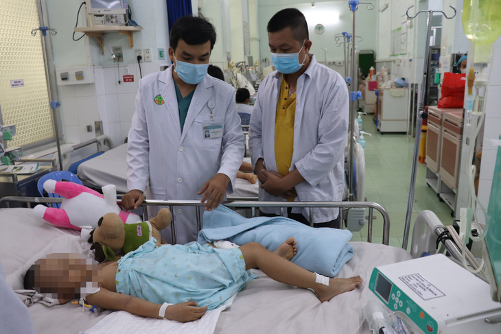 Bác sĩ CKI Võ Thành Luân, phó trưởng khoa hồi sức nhiễm và COVID-19 Bệnh viện Nhi đồng 2, trao đổi tình hình sức khỏe của bé với người nhà - Ảnh: Bệnh viện cung cấp