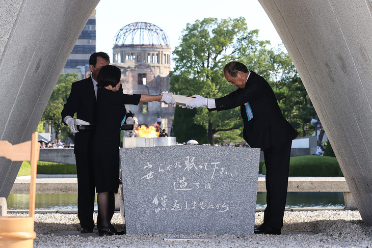 Thị trưởng thành phố Hiroshima, ông Matsui Kazumi (bìa phải) và đại diện gia đình nạn nhân lưu giữ cuốn sổ ghi lại tên các nạn nhân trong thảm họa bom nguyên tử năm 1945 - Ảnh: AFP