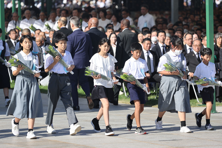 Các em học sinh Nhật Bản dâng hoa tưởng niệm các nạn nhân trong thảm họa - Ảnh: AFP