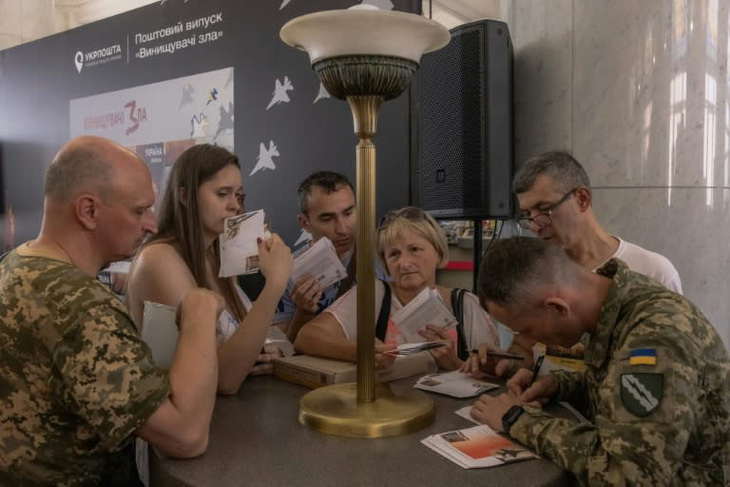Người dân Ukraine xếp hàng mua tem mới có chữ ký của một phi công Ukraine - Ảnh: AFP