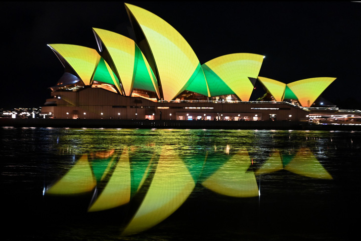 Nhà hát Opera Sydney được chiếu sáng bằng màu xanh lục và vàng trong đêm 7-8 để cổ vũ đội tuyển bóng đá nữ Úc trước trận đấu loại trực tiếp đầu tiên ở vòng loại trực tiếp World Cup với Đan Mạch. Trong trận đấu này, Úc thắng Đan Mạch 2-0 - Ảnh: AFP