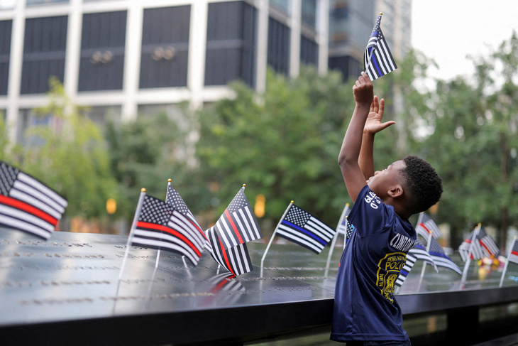 Một cậu bé cầm cờ vào ngày kỷ niệm 22 năm vụ tấn công ngày 11-9-2001 vào Trung tâm Thương mại Thế giới tại Đài tưởng niệm & Bảo tàng Quốc gia ngày 11-9, ở thành phố New York, Mỹ, ngày 11-9 - Ảnh: REUTERS