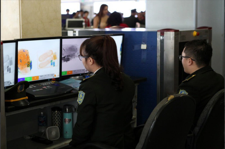 Nhân viên an ninh hàng không Tân Sơn Nhất soi chiếu hành lý xách tay của hành khách - Ảnh: TUẤN PHÙNG