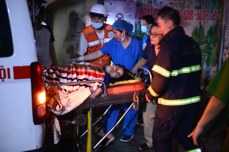 Cảnh sát, nhân viên y tế và người dân đưa các nạn nhân trong đám cháy đi cấp cứu - Ảnh: DANH TRỌNG