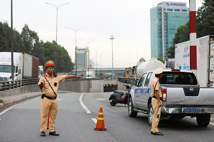 Lực lượng cảnh sát giao thông tạm thời &quot;phong tỏa&quot; hầm chui, hướng dẫn xe cộ đi trên quốc lộ 51 song song với hầm chui để khắc phục sự cố - Ảnh: AN BÌNH