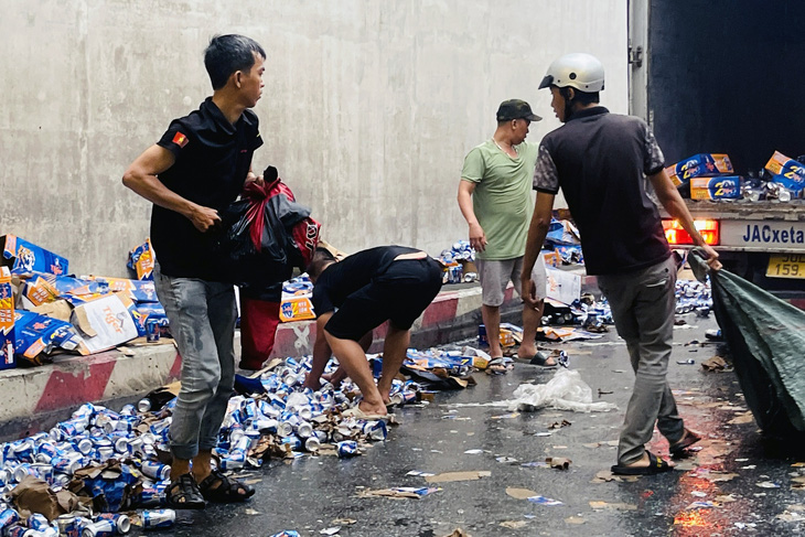 Người dân hỗ trợ tài xế thu gom bia rơi vãi ra đường sau sự cố - Ảnh: AN BÌNH