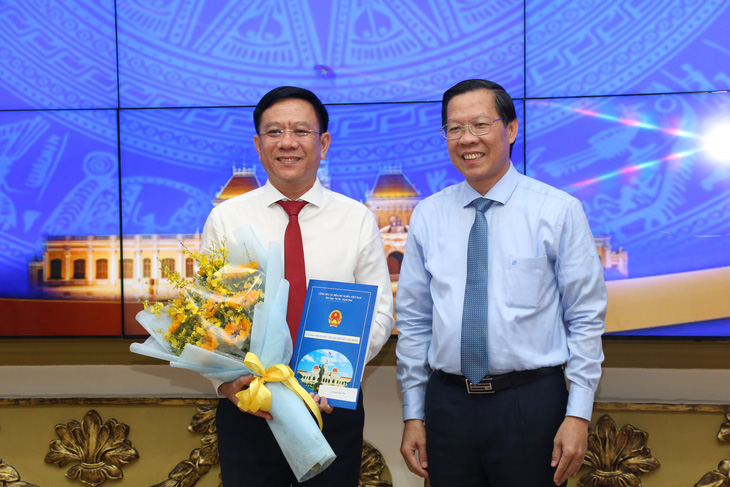 Chủ tịch UBND TP.HCM Phan Văn Mãi trao quyết định và tặng hoa chúc mừng ông Nguyễn Ngọc Hồi (trái) - Ảnh: THẢO LÊ