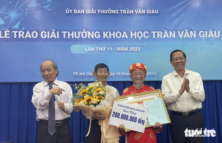 Nhà sử học Nguyễn Đình Tư được trao chứng nhận, hoa và bảng tượng trưng 200 triệu đồng từ các đại biểu, trong đó có ông Phan Văn Mãi - chủ tịch UBND TP.HCM (bìa phải) - Ảnh: THÁI THÁI