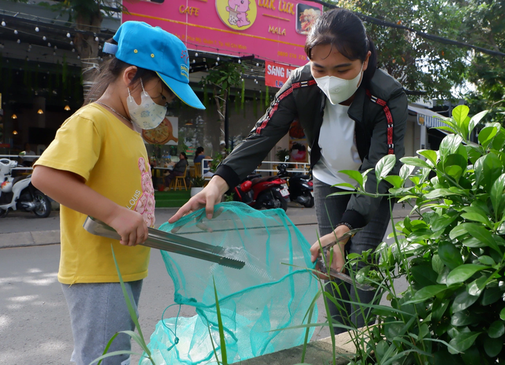 Hai mẹ con bé Nguyễn Ngọc Đông Nghi (4 tuổi) cùng đi bộ nhặt rác tại khu vực chợ Phước Long, phường Phú Mỹ (quận 7, TP.HCM) - Ảnh: K.ANH