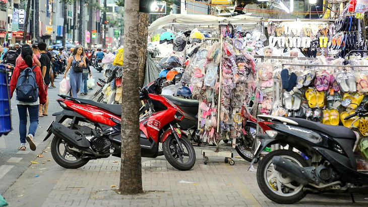 Vỉa hè đường Nguyễn Trãi (quận 5) bị các cửa hàng thời trang lấn chiếm không có lối cho người đi bộ - Ảnh: PHƯƠNG QUYÊN