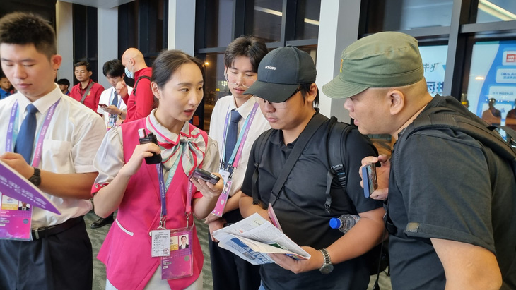 Tình nguyện viên của ban tổ chức (trái) tận hình hướng dẫn các nhà báo Việt Nam đến Trung Quốc tác nghiệp tại Asiad 19 - Ảnh: H.Đ.