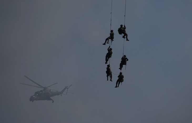 Các binh sĩ Ba Lan cheo leo trên dây thừng cùng trực thăng chiến đấu Mi-24 tham gia cuộc diễn tập tại một địa điểm ở Bemowo Piskie, thị trấn Orzysz (đông bắc Ba Lan) ngày 16-9. Cuộc diễn tập này diễn ra trước sự kiện triển lãm pháo mang tên "Autumn Fire 23" - Ảnh: REUTERS