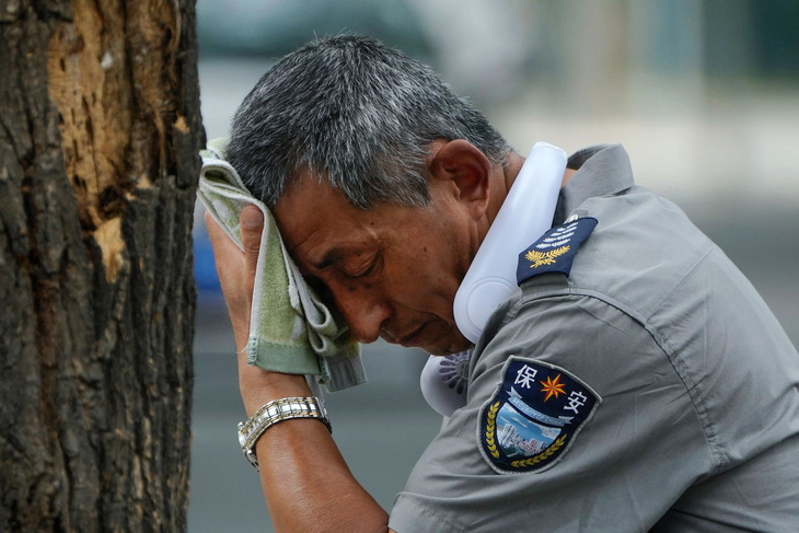 Một người đàn ông lau mồ hôi dù đã đeo quạt điện ở cổ tại thành phố Thượng Hải hồi đầu tháng 7 vừa qua - Ảnh: SCMP