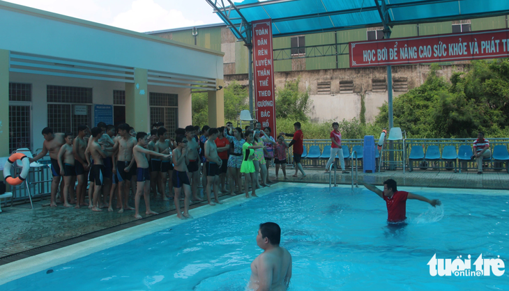 Các huấn luyện viên hướng dẫn kỹ năng bơi cho các em học - Ảnh: HOÀI THƯƠNG