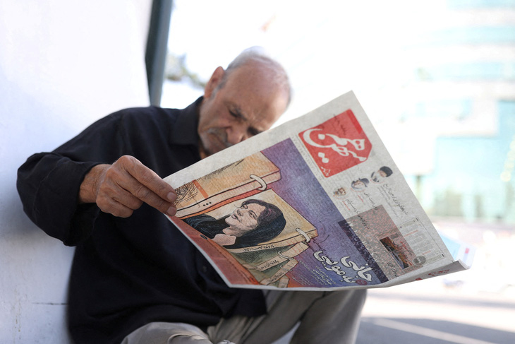 Một người đàn ông xem tờ báo có ảnh bìa là hình Mahsa Amini ở Tehran, Iran, ngày 18-9-2022 - Ảnh: REUTERS