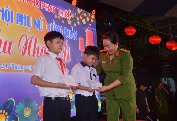 Thượng tá Vũ Thị Thu Hà, phó trưởng Công an TP Phan Thiết, trao quà hỗ trợ cho hai con trai anh Nguyễn Hữu Đốn - Ảnh: ĐỨC TRONG