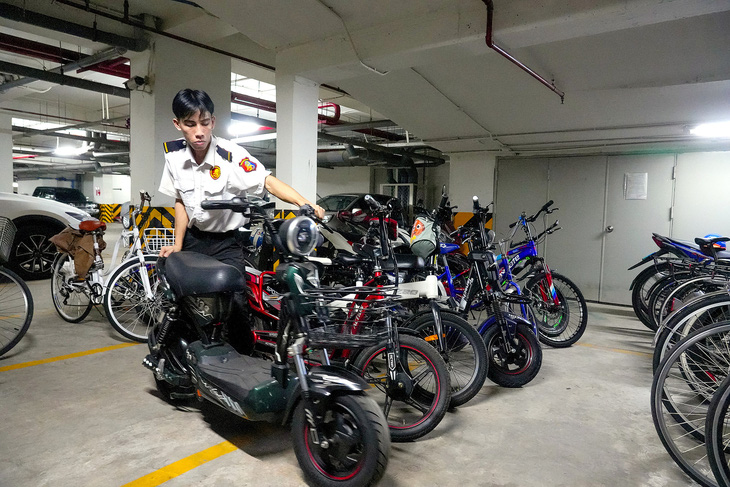 Nhân viên bảo vệ sắp xếp xe điện của cư dân tại một chung cư ở quận Tân Phú, TP.HCM - Ảnh: HỮU HẠNH