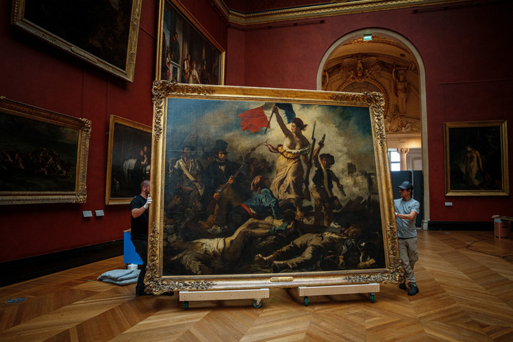 Công nhân di dời bức tranh "Liberty Leading the People" (Nữ thần Tự do dẫn dắt nhân dân) ở bảo tàng Louvre tại Paris để đi sửa chữa hôm 20-9. Việc sửa chữa tác phẩm nổi tiếng của họa sĩ theo trường phái lãng mạn Eugène Delacroix (1798 - 1863) sẽ kéo dài đến mùa xuân 2024. Ảnh: AFP 