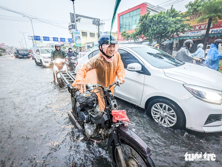 Một thanh niên dắt xe qua đoạn ngập trên đường Tôn Đức Thắng do xe ngập nước chết máy - Ảnh: TẤN LỰC