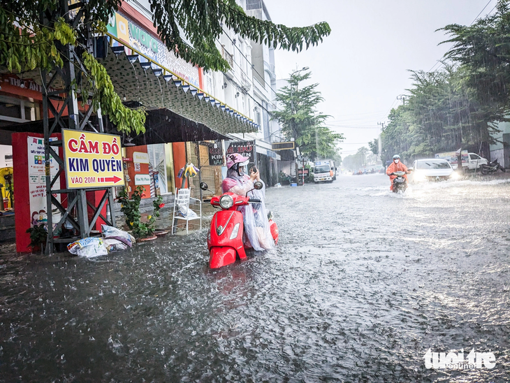 Người phụ nữ gọi điện thoại cầu cứu người thân vì xe bị ngập nước chết máy khi vào đường Tôn Đức Thắng - Ảnh: TẤN LỰC