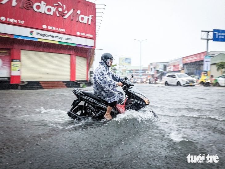 Một người đàn ông băng xe máy vượt qua khu vực ngập nước - Ảnh: TẤN LỰC
