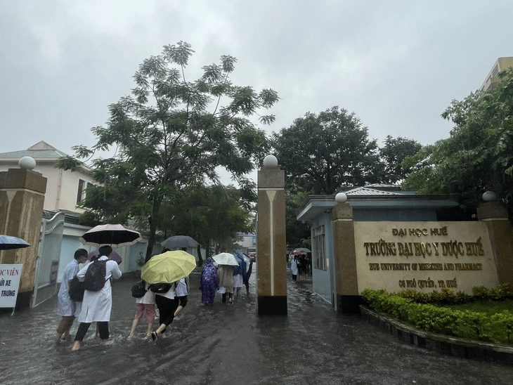Sinh viên Trường đại học Y Dược Huế bì bõm lội nước trong cơn mưa lớn - Ảnh: NGUYỄN TRỌNG