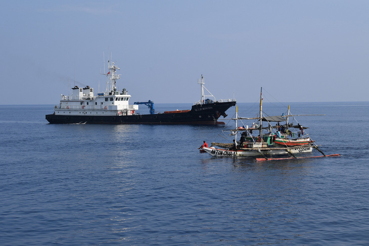 Tàu đánh cá Philippines (phải) đi ngang tàu Trung Quốc gần bãi cạn Scarborough ngày 20-9 - Ảnh: AFP