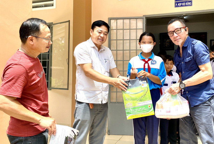 Ông Lâm Tấn Lợi - giám đốc Công ty Duy Lợi (phải) và ông Ngô Đăng Thành - trưởng Phòng Giáo dục và Đào tạo huyện Định Quán (trái) trao quà cho các em học sinh - Ảnh: NGỌC TRÂM