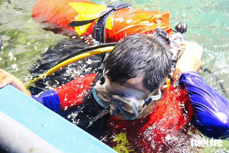 Một thợ lặn chuẩn bị trình diễn múa lân dưới nước - Ảnh: TRẦN HOÀI